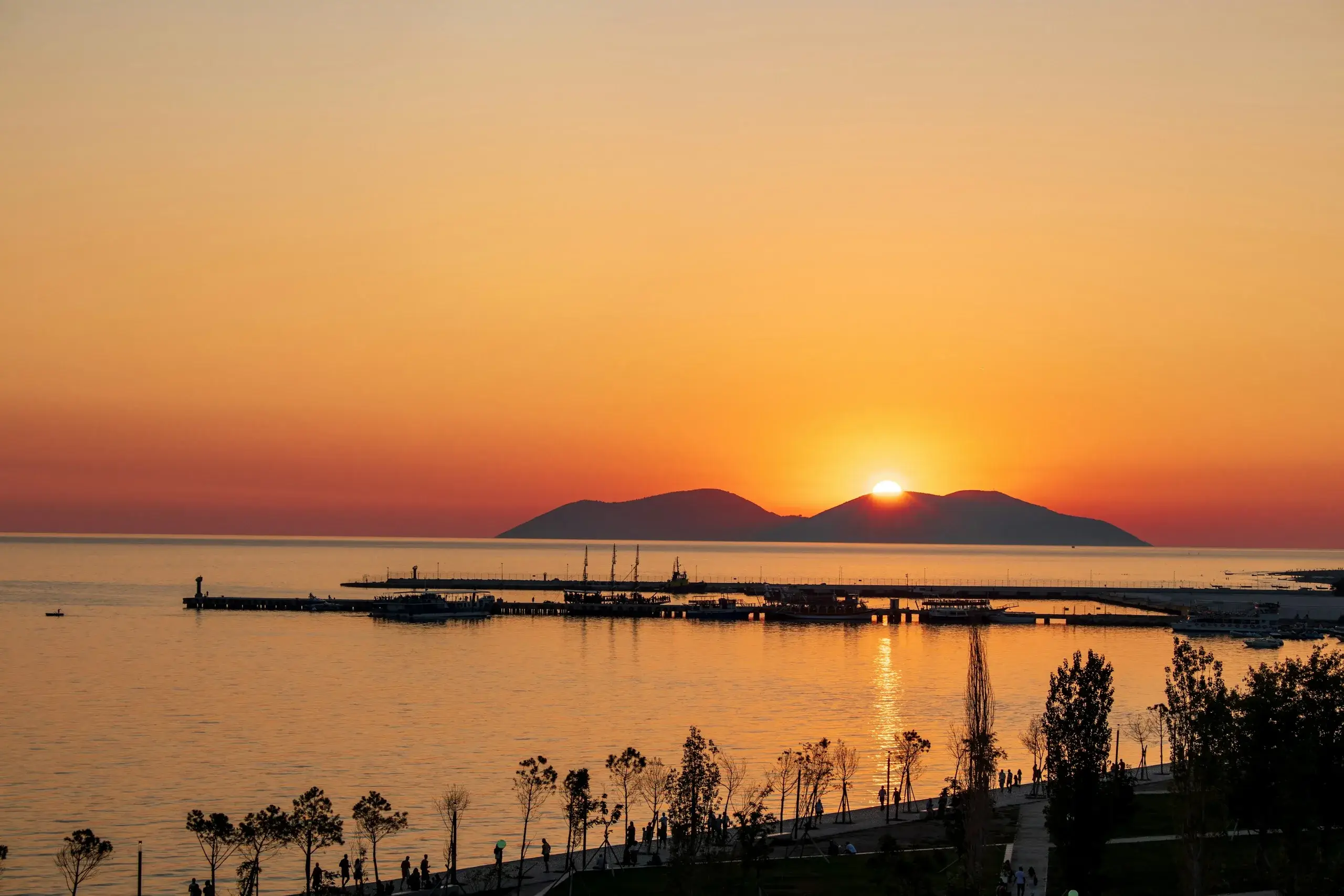 Sunset behind Sazan Island, seen over the harbour and seafront promenade of Vlorë