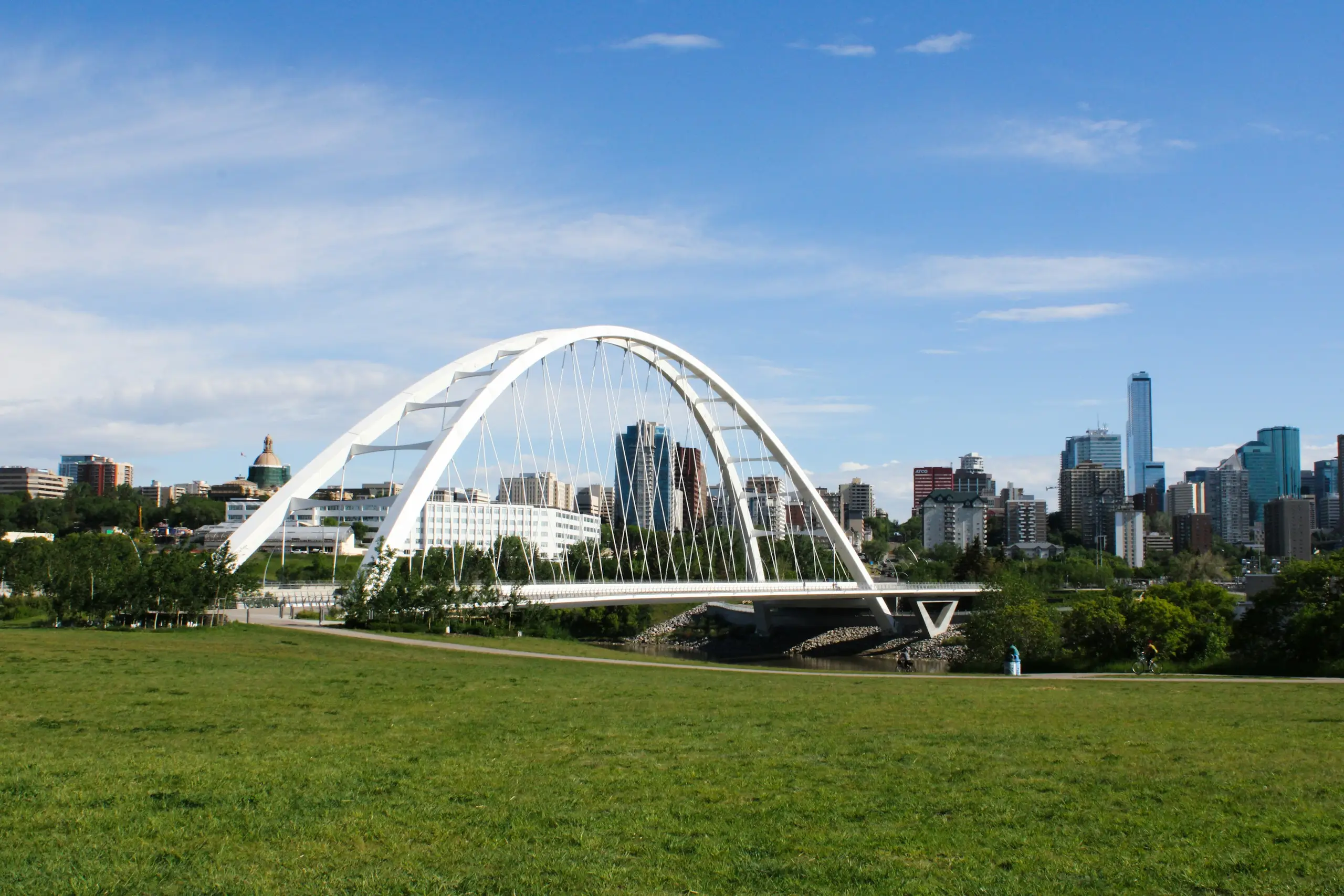 The white arch of the Walterdale Bridge over the river with the downtown Edmonton skyline behind