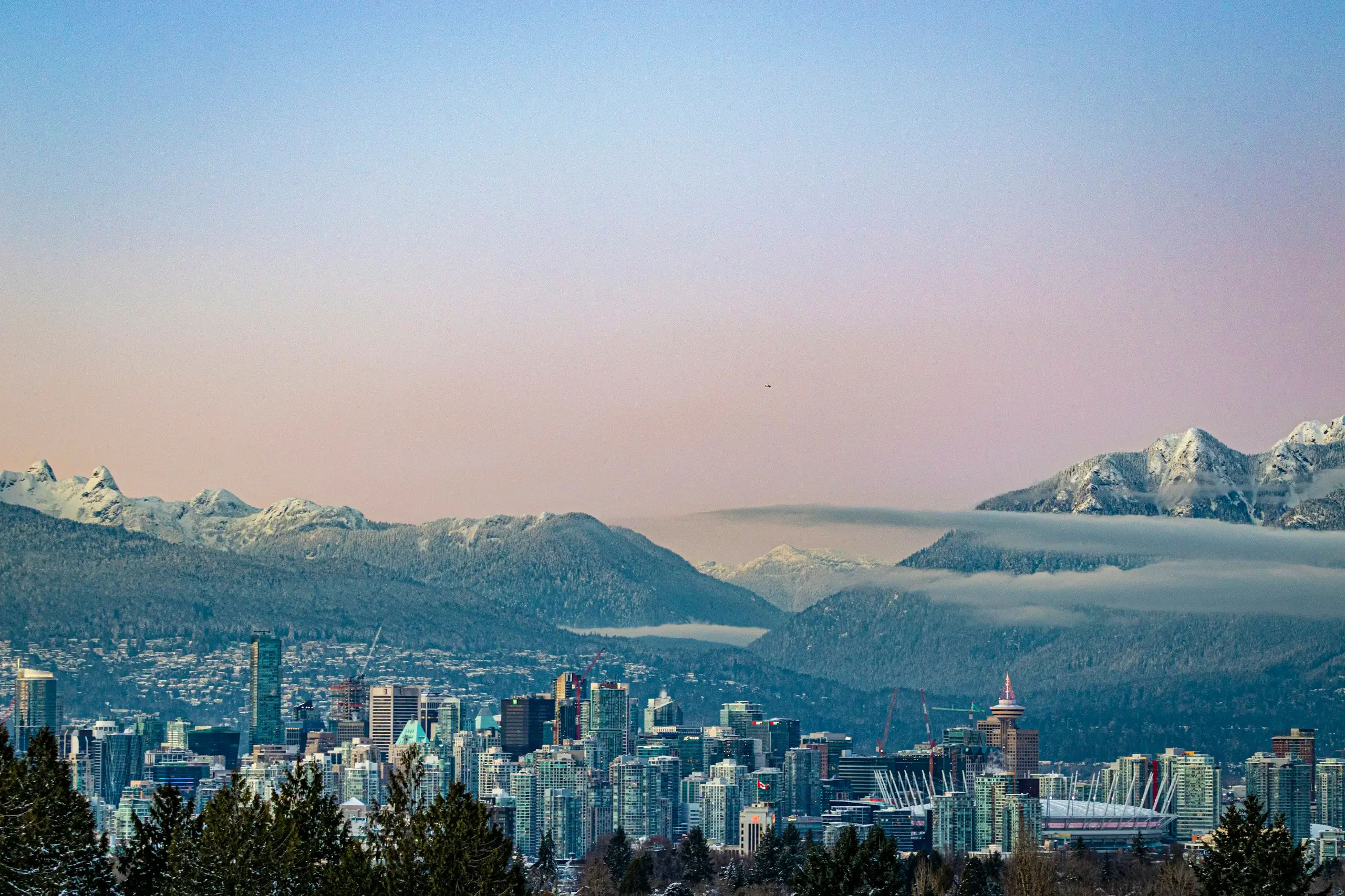 The Vancouver skyline below the snow-capped North Shore mountains at dusk
