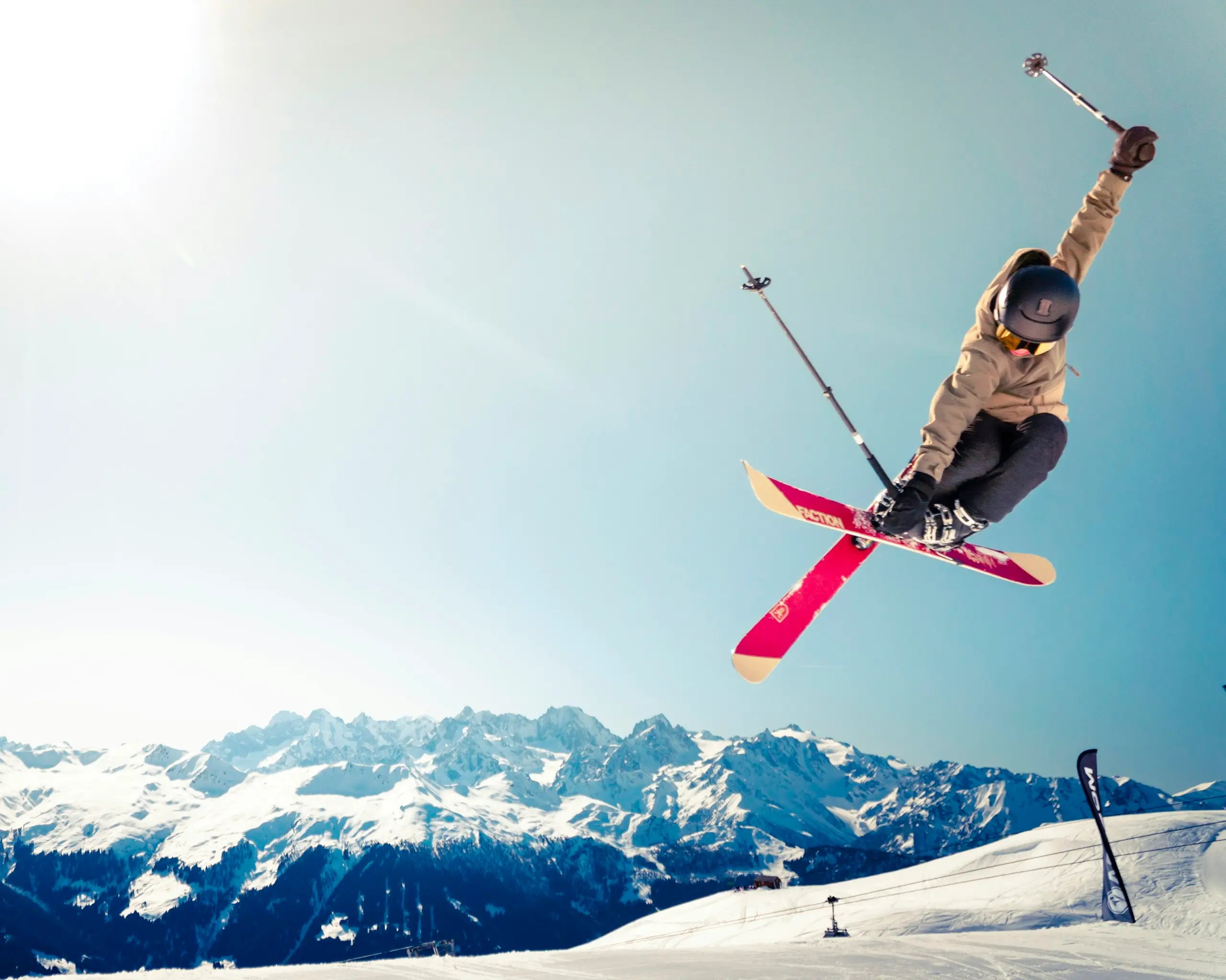 A skier mid-jump above snow-covered peaks