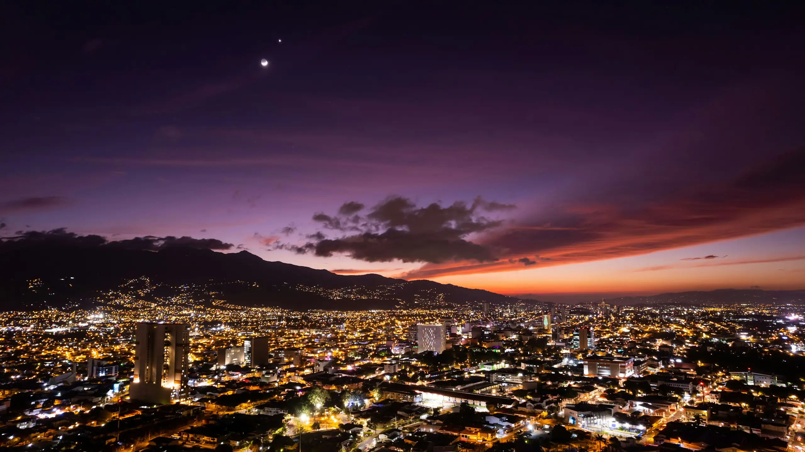 The lights of San Jose spread below dark mountains under a deep dusk sky, Costa Rica