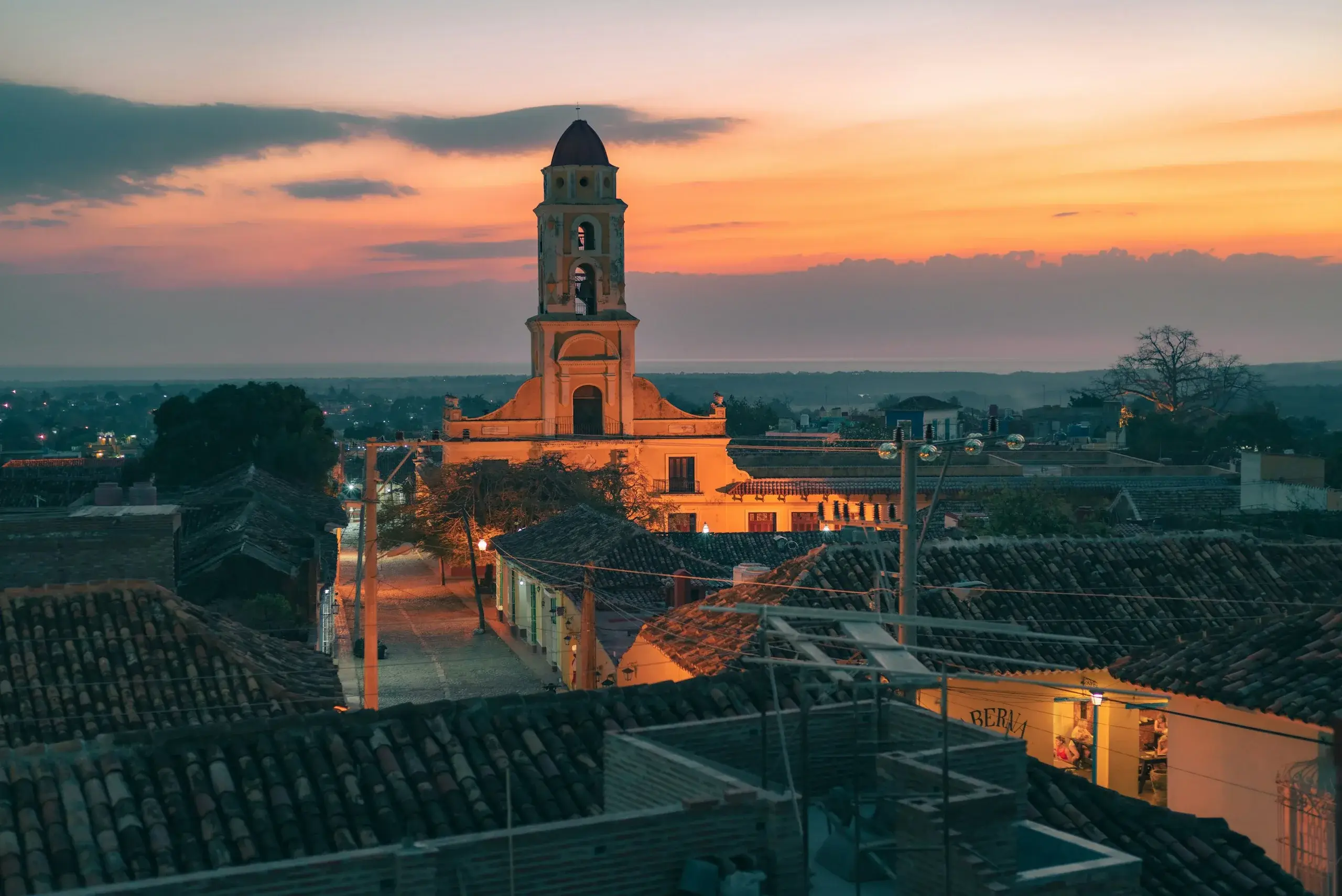 Bell tower rising over the tiled rooftops of Trinidad at sunset