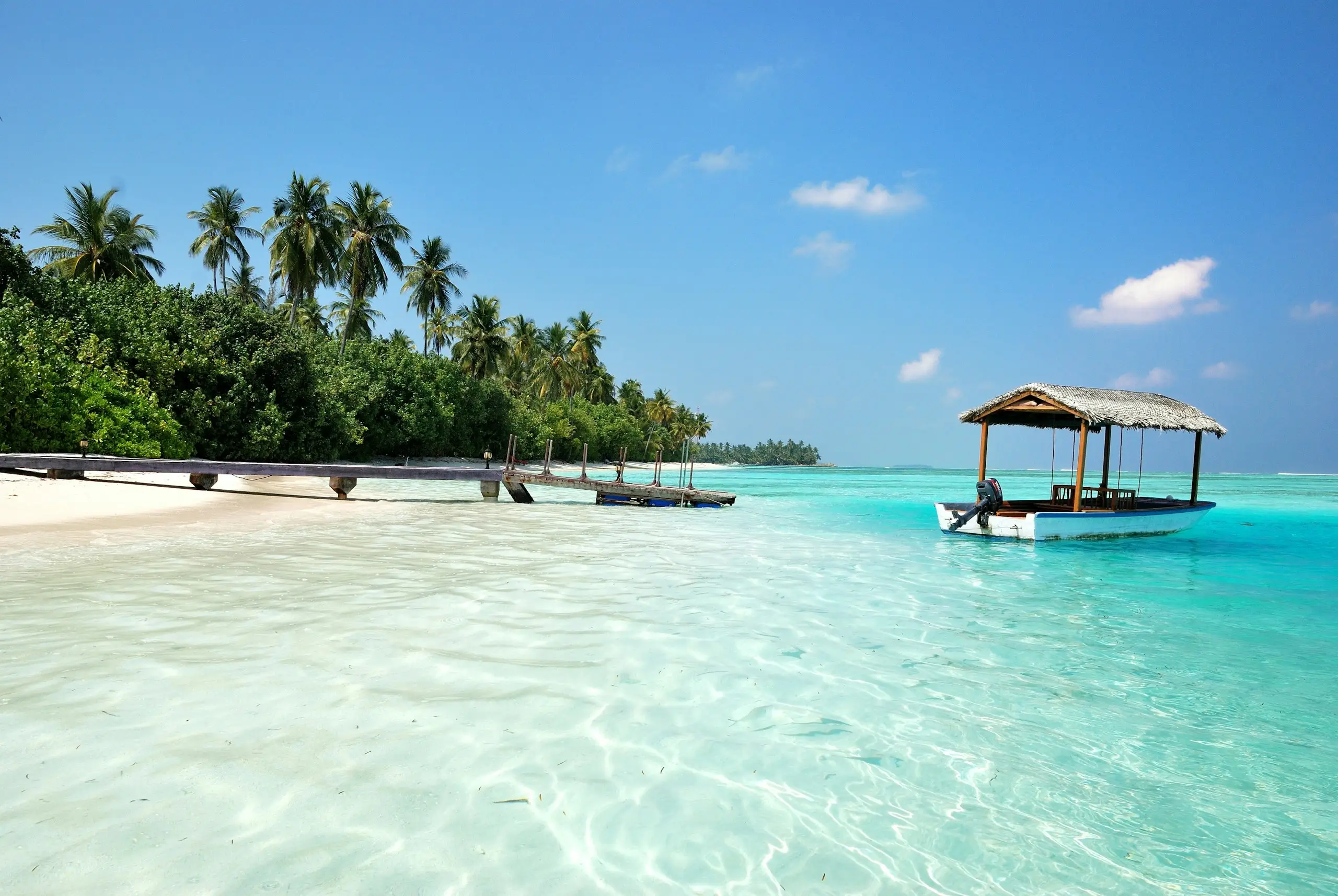 Turquoise shallows and a thatched boat shelter off a white-sand beach