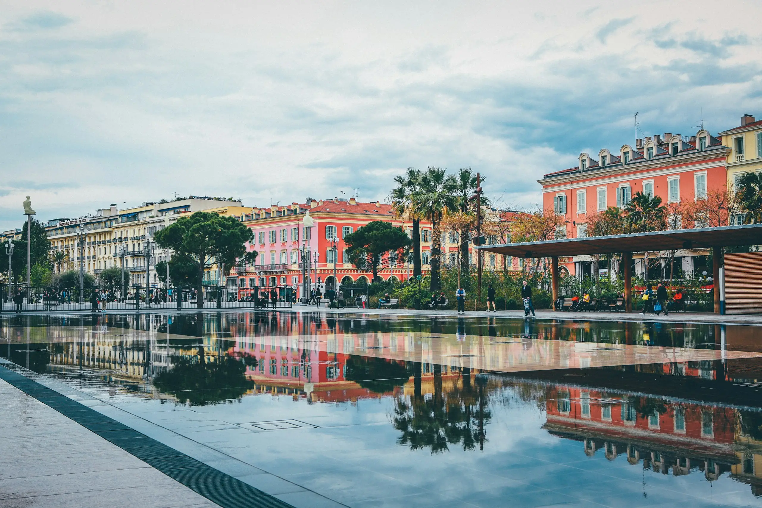 Palm trees and pastel facades reflected in a pool, Nice