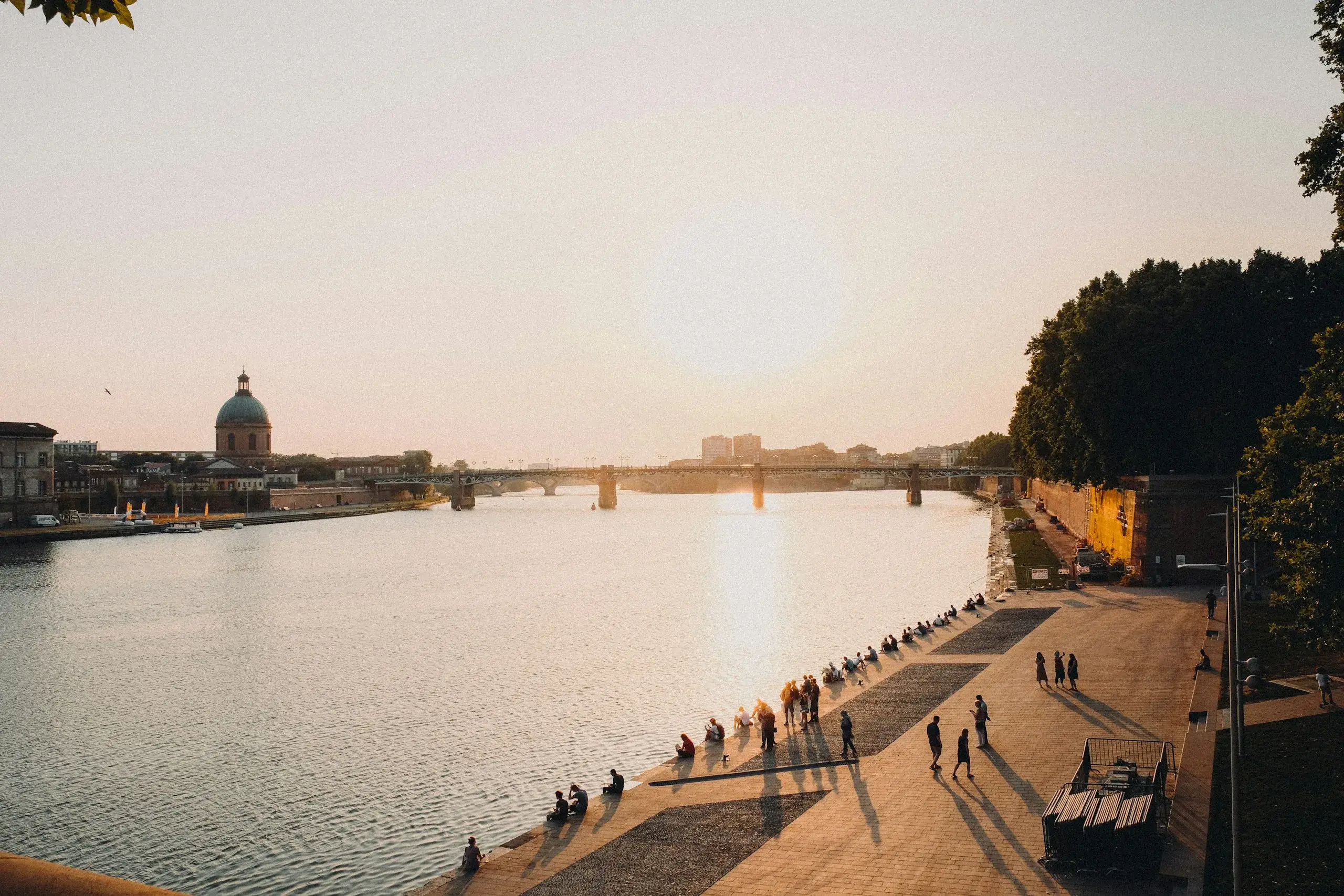 People strolling the Garonne riverbank in Toulouse at sunset