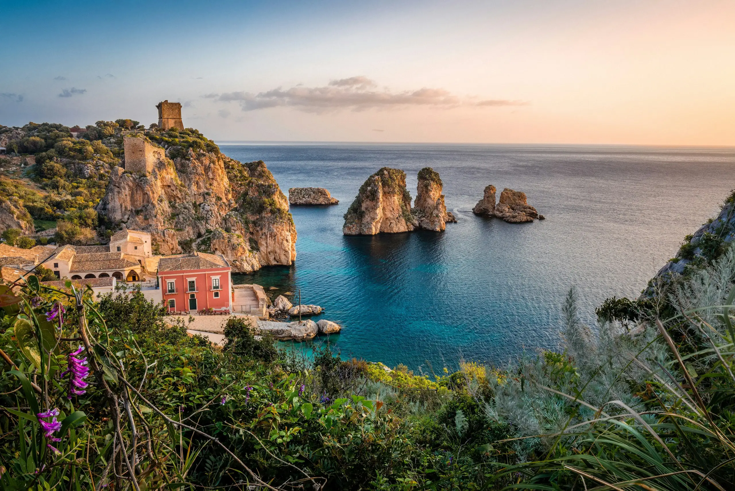 Sea stacks and a coastal tower on Sicily's coast at sunset