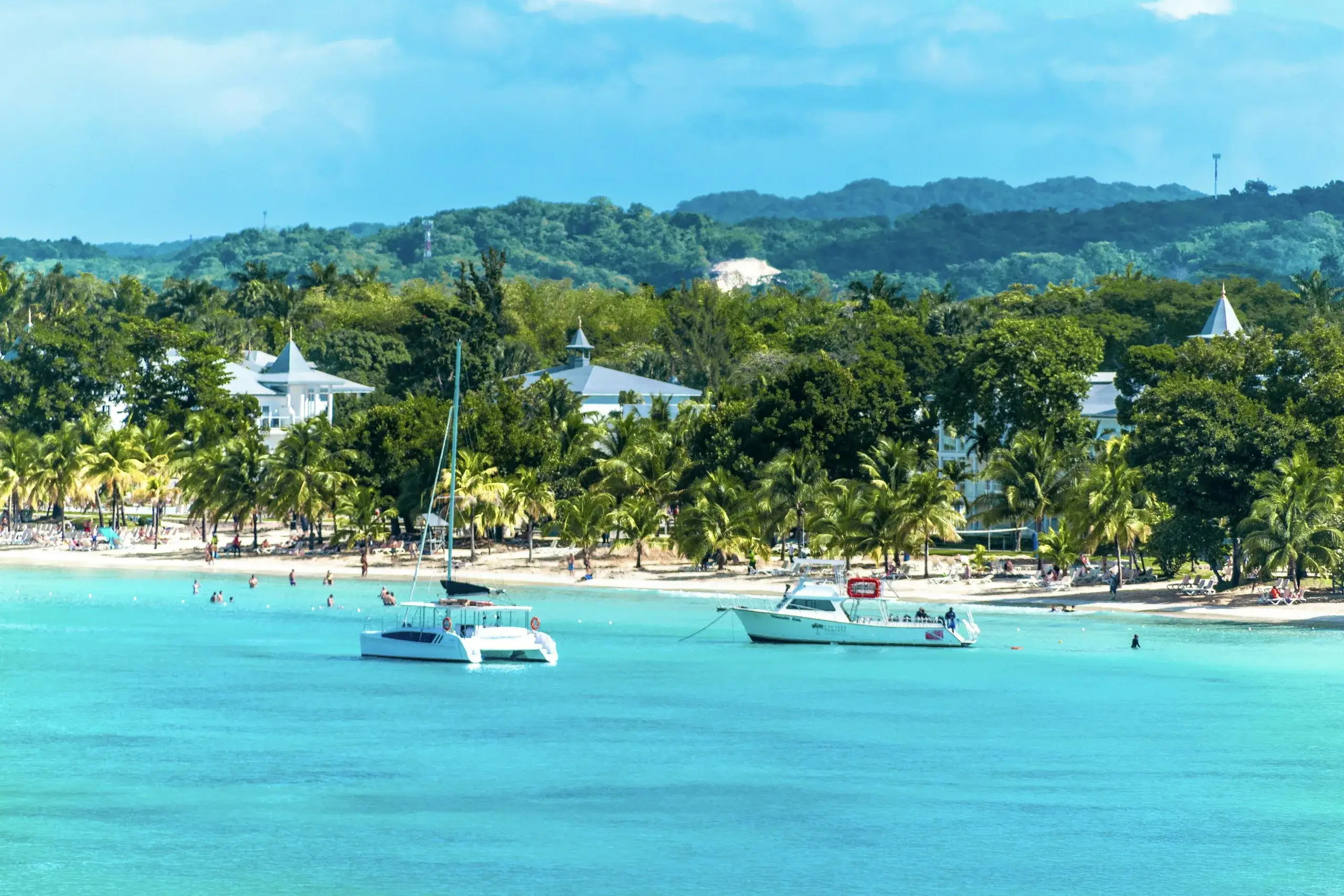 Boats anchored in turquoise water off a palm-lined beach on Jamaica's south coast
