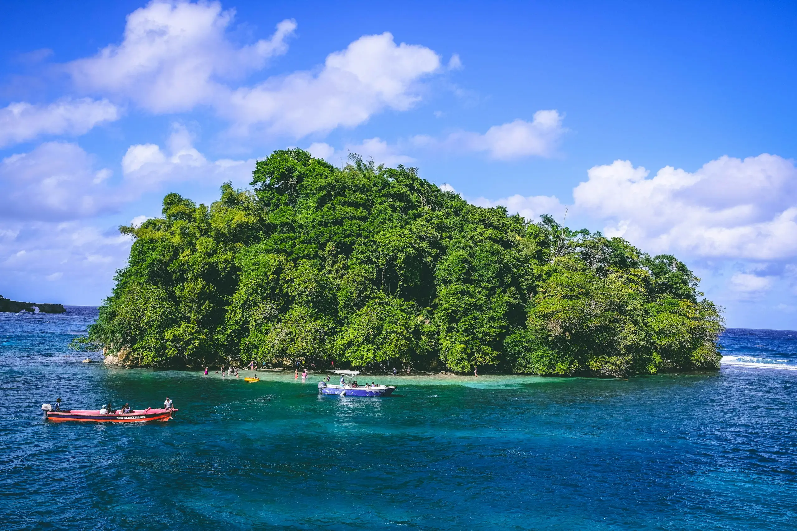 Small boats moored off a lush green islet in Jamaica