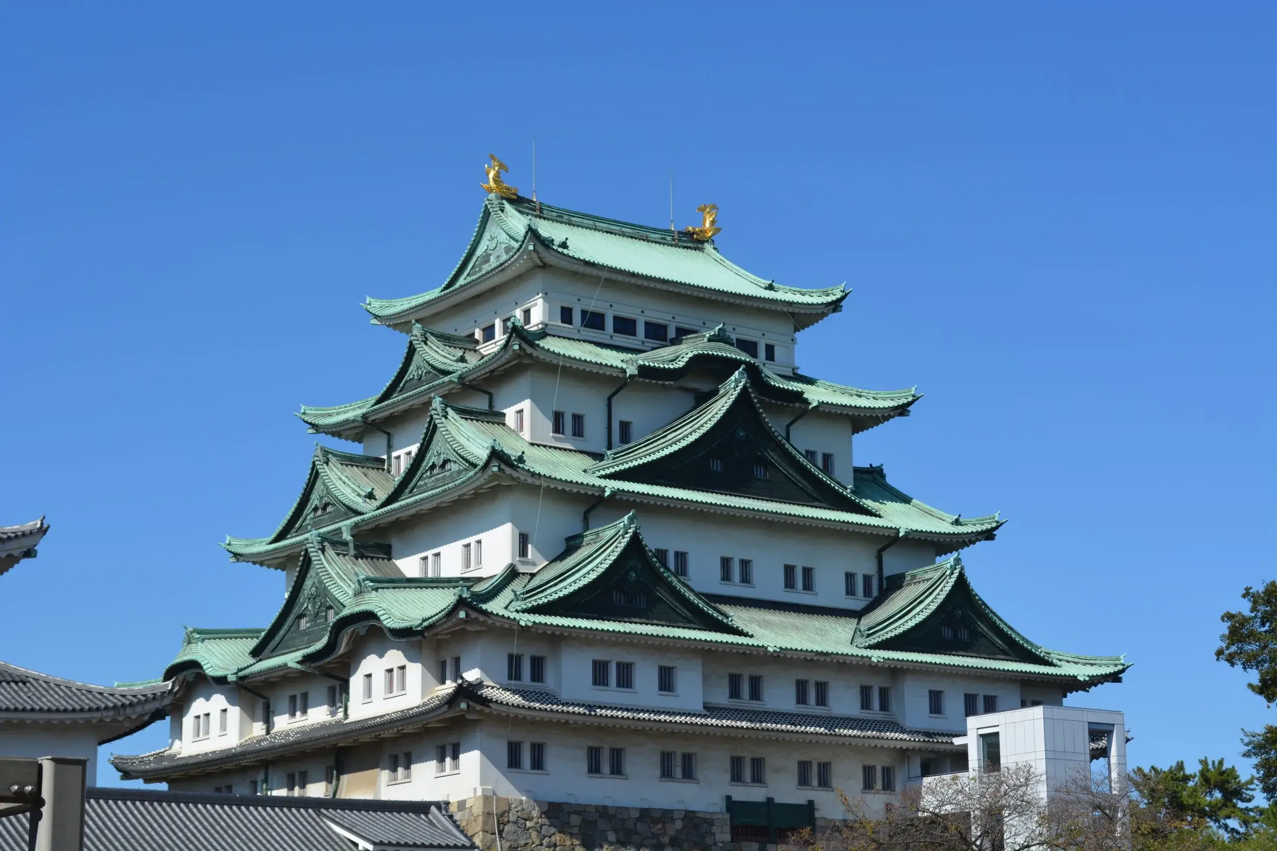 Le château de Nagoya, ses toits verts et ses ornements dorés sous un ciel bleu