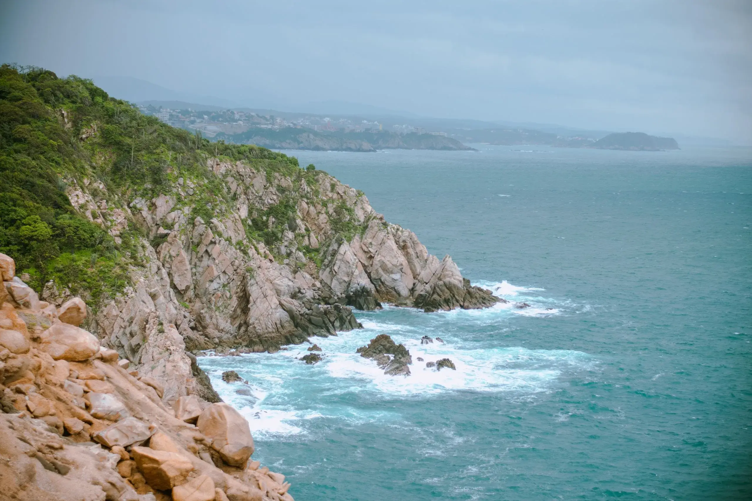 Rocky cliffs and green hills meeting the Pacific near Huatulco