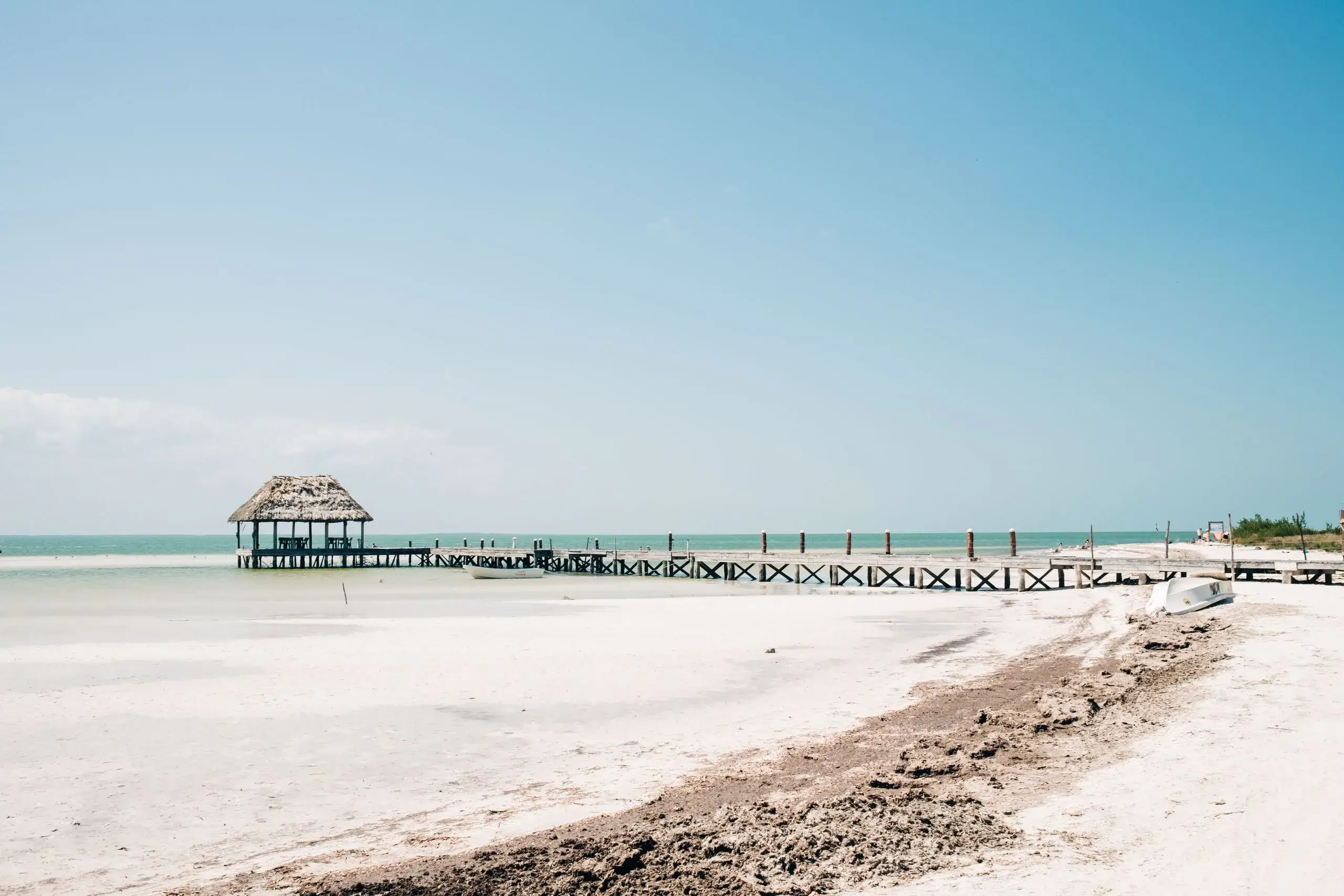Thatched palapa at the end of a pier over calm water on Isla Holbox