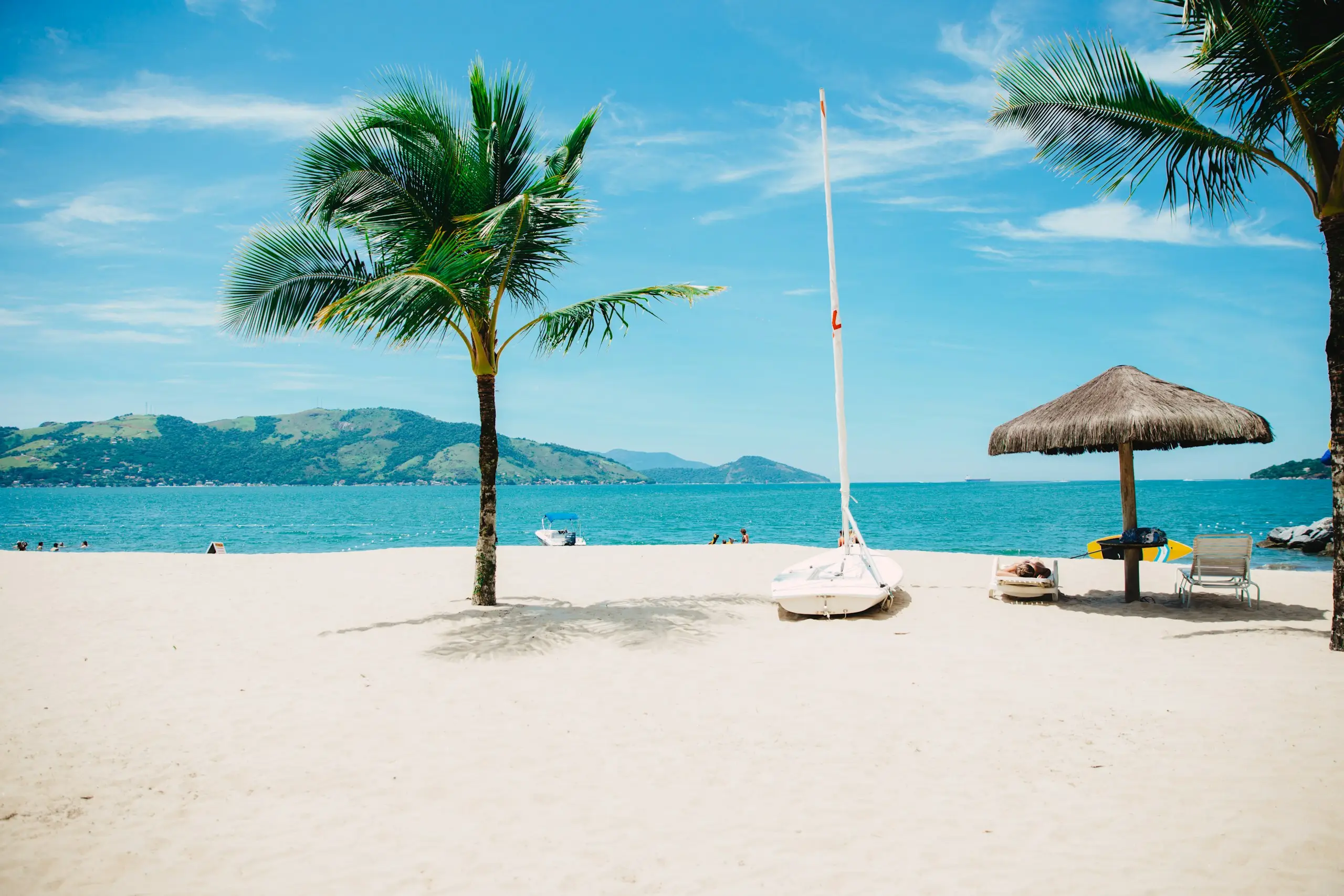 Palm trees and a thatched umbrella on a white-sand beach, Loreto