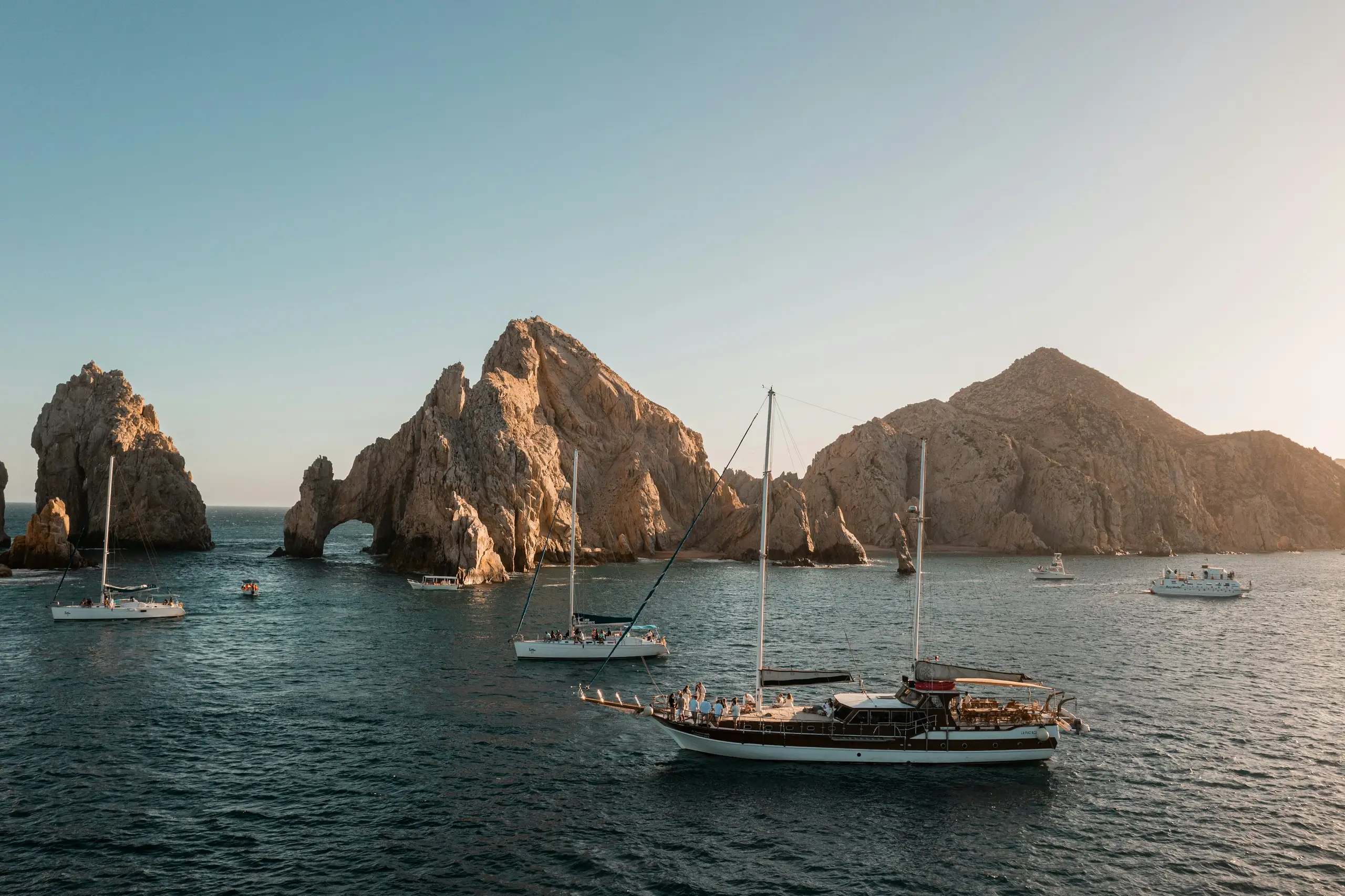 Sailboats gathered near the El Arco rock formation at golden hour, Los Cabos, Mexico