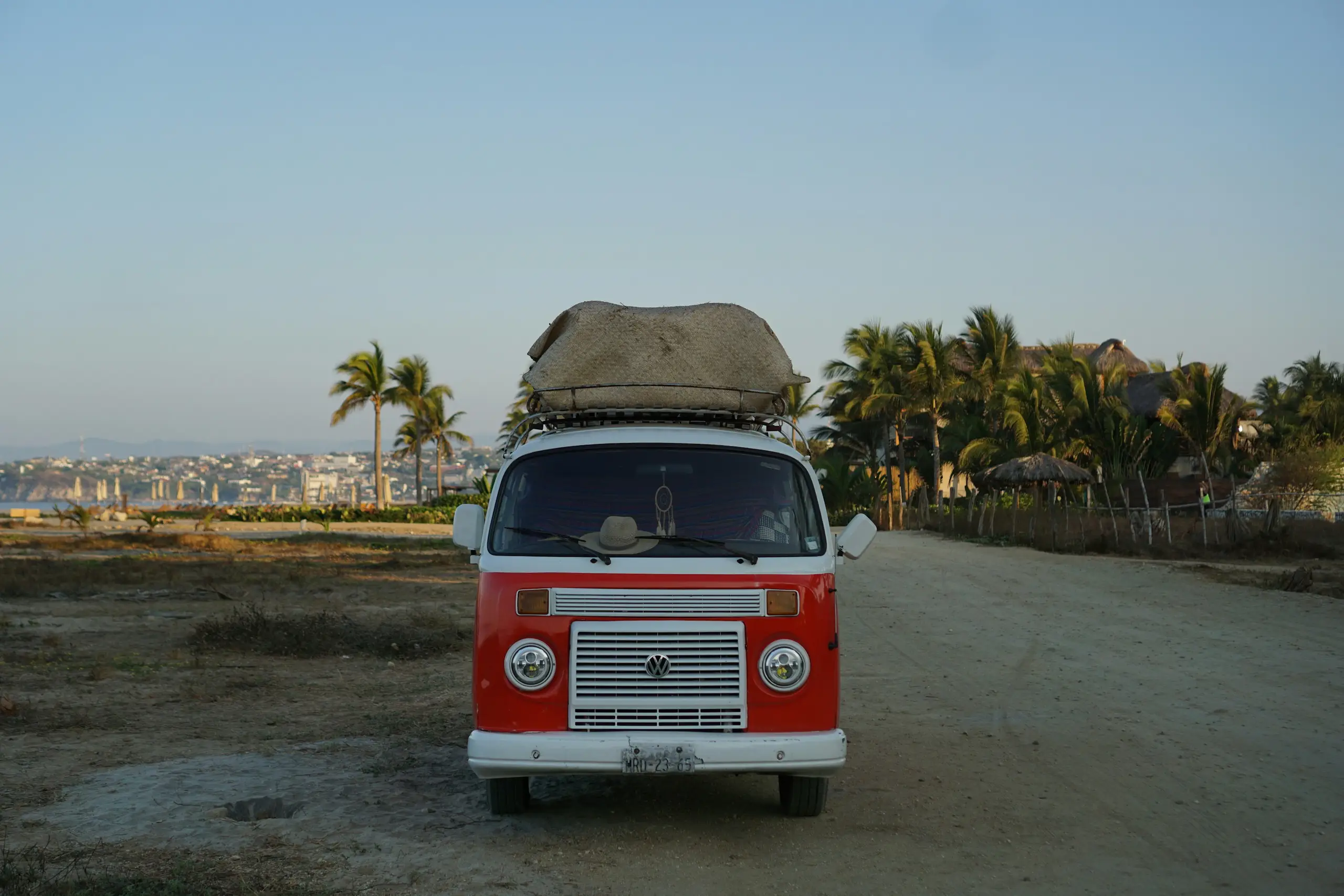 A classic red and white campervan parked on a sandy road above the beach town, Puerto Escondido, Mexico