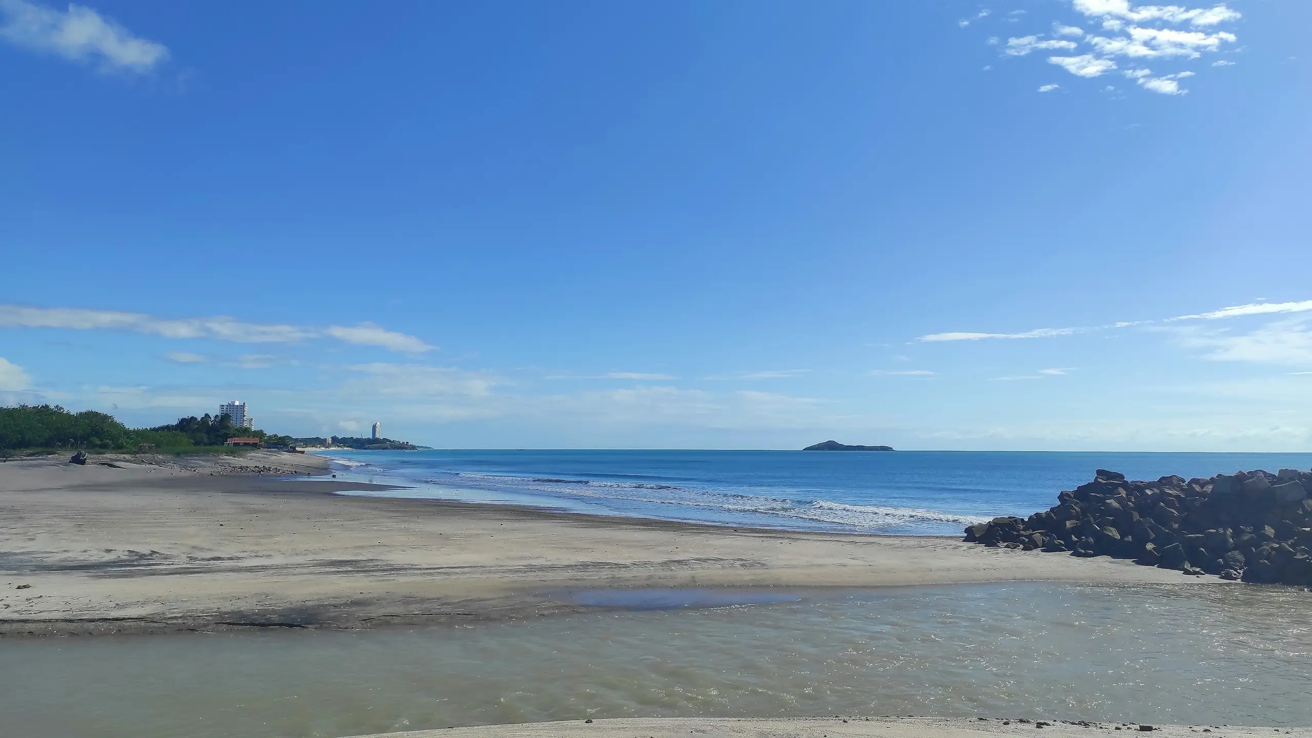 A wide quiet sandy beach with gentle surf and a distant headland, Playa Blanca, Panama