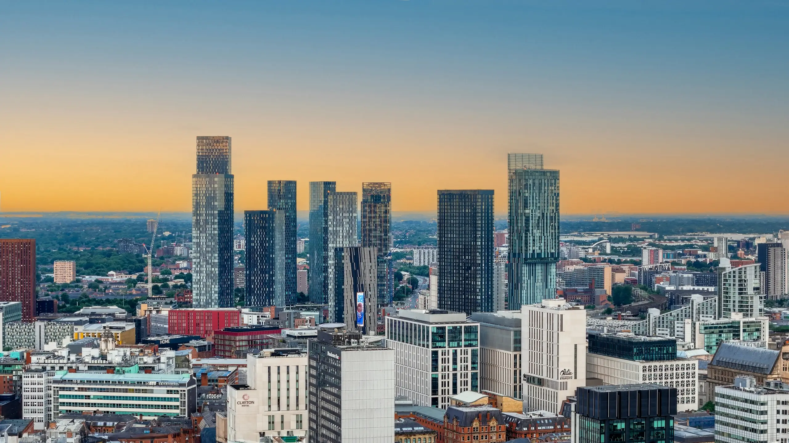The Manchester skyline of glass towers glowing at sunset, England