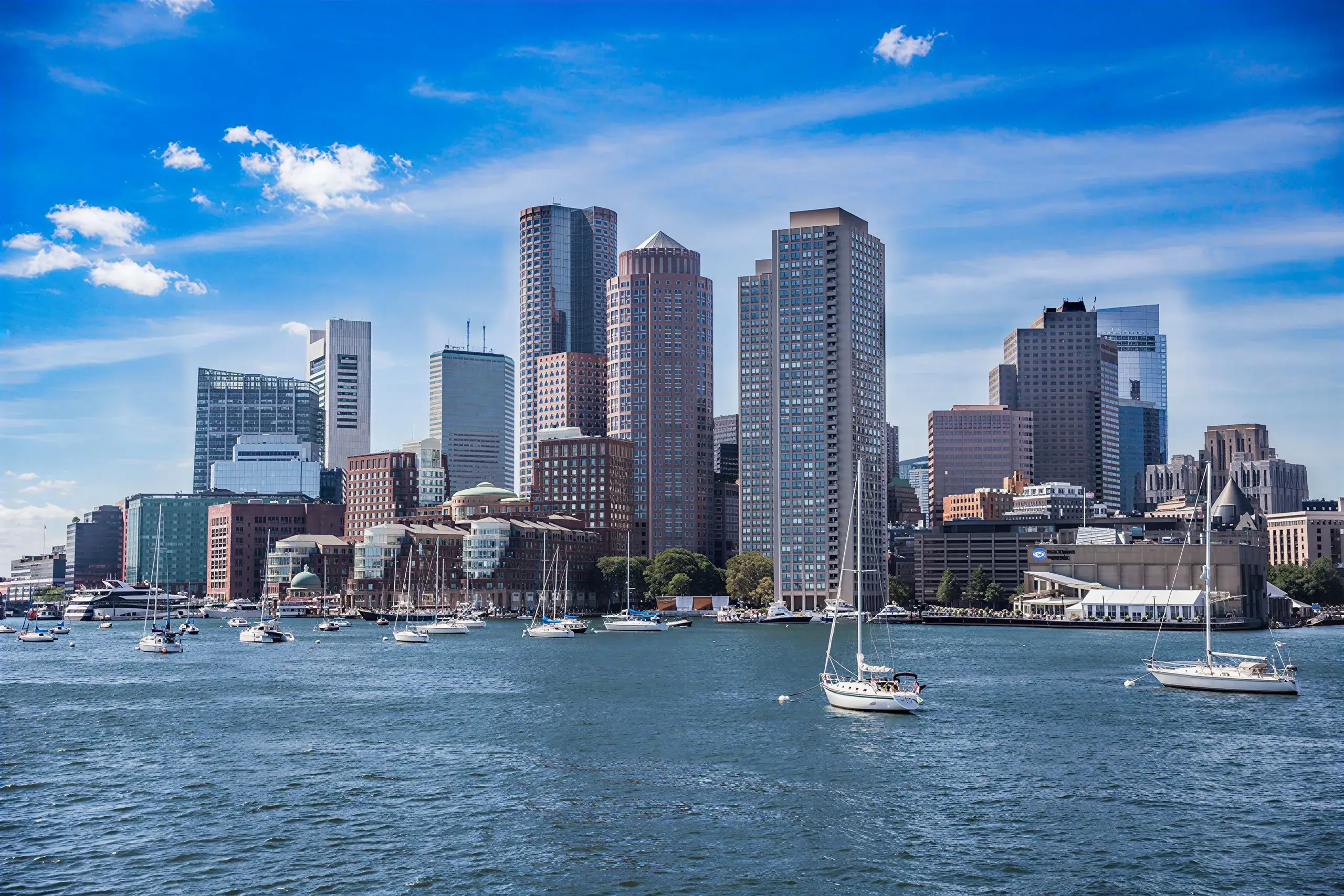 Boston's downtown skyline and moored sailboats across the harbour on a sunny day