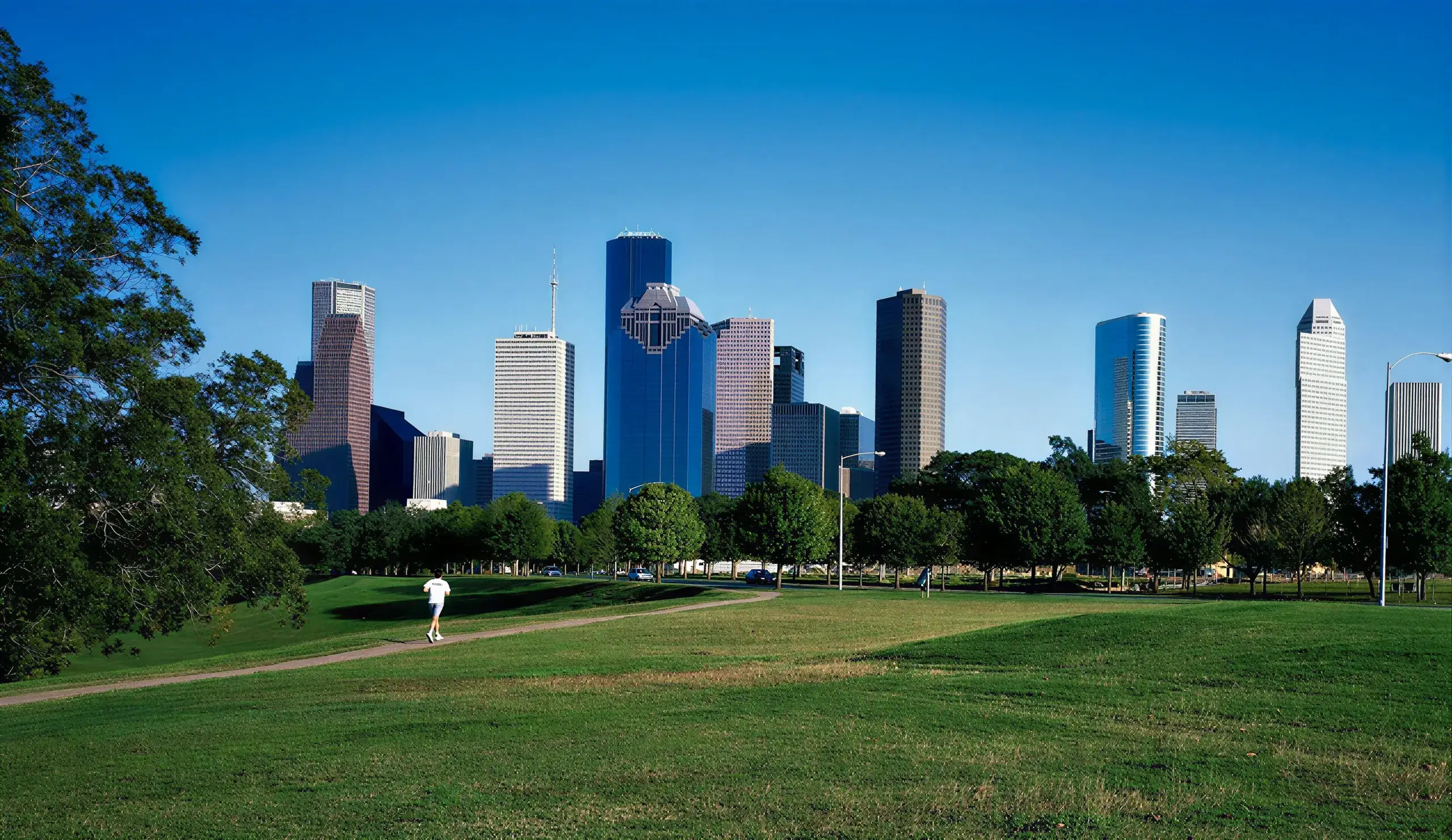 Downtown Houston skyline rising above the trees and lawns of a city park
