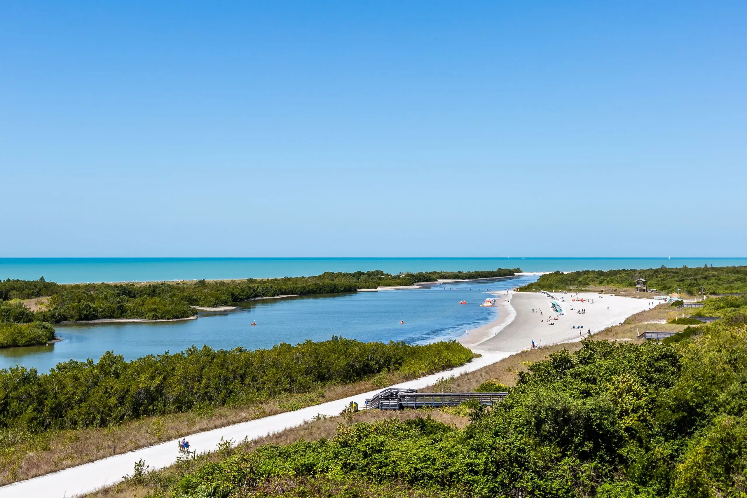 Boardwalk and white sand beach beside a calm lagoon on Marco Island