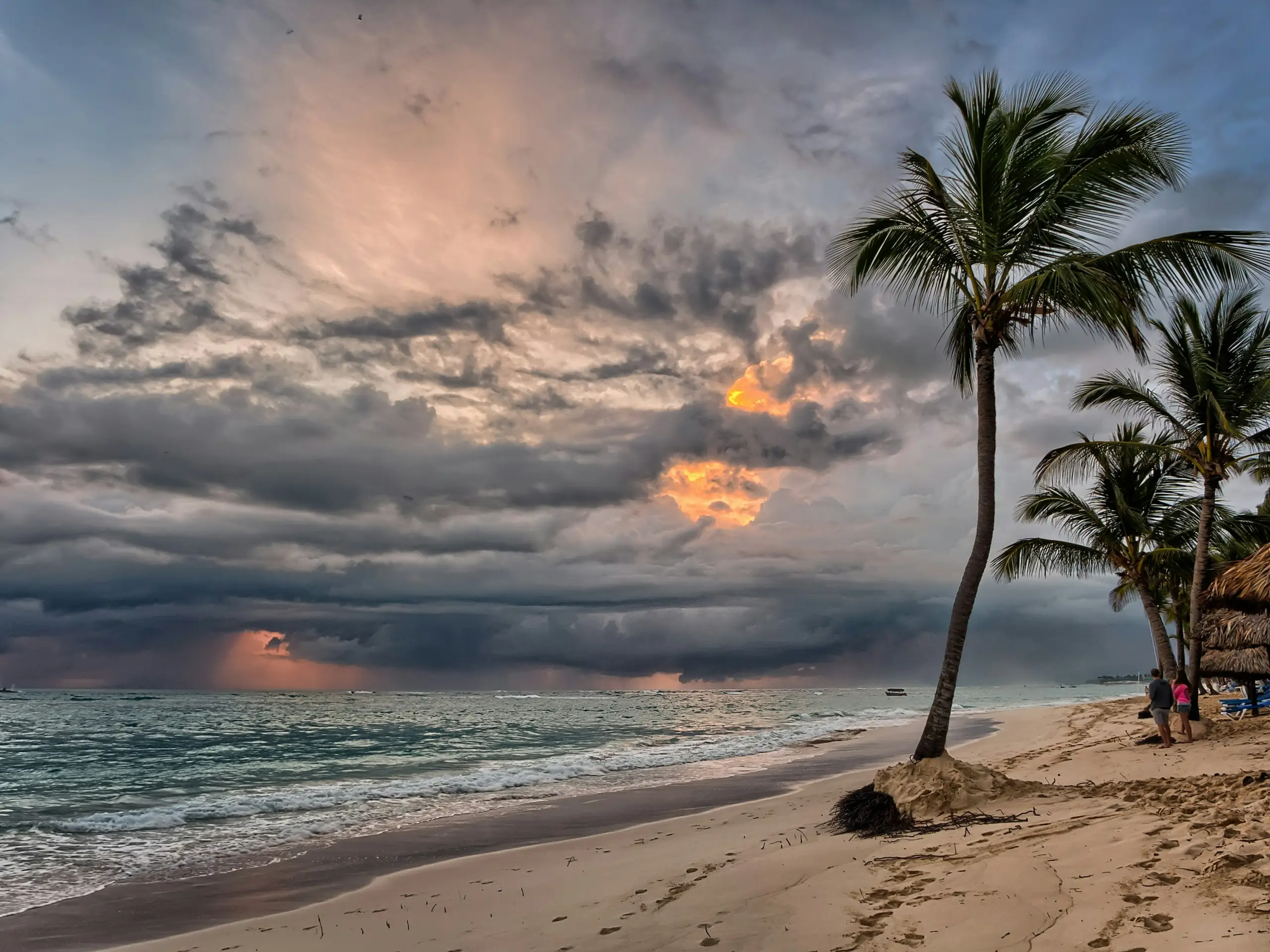 Storm clouds building over a Caribbean beach with palm trees